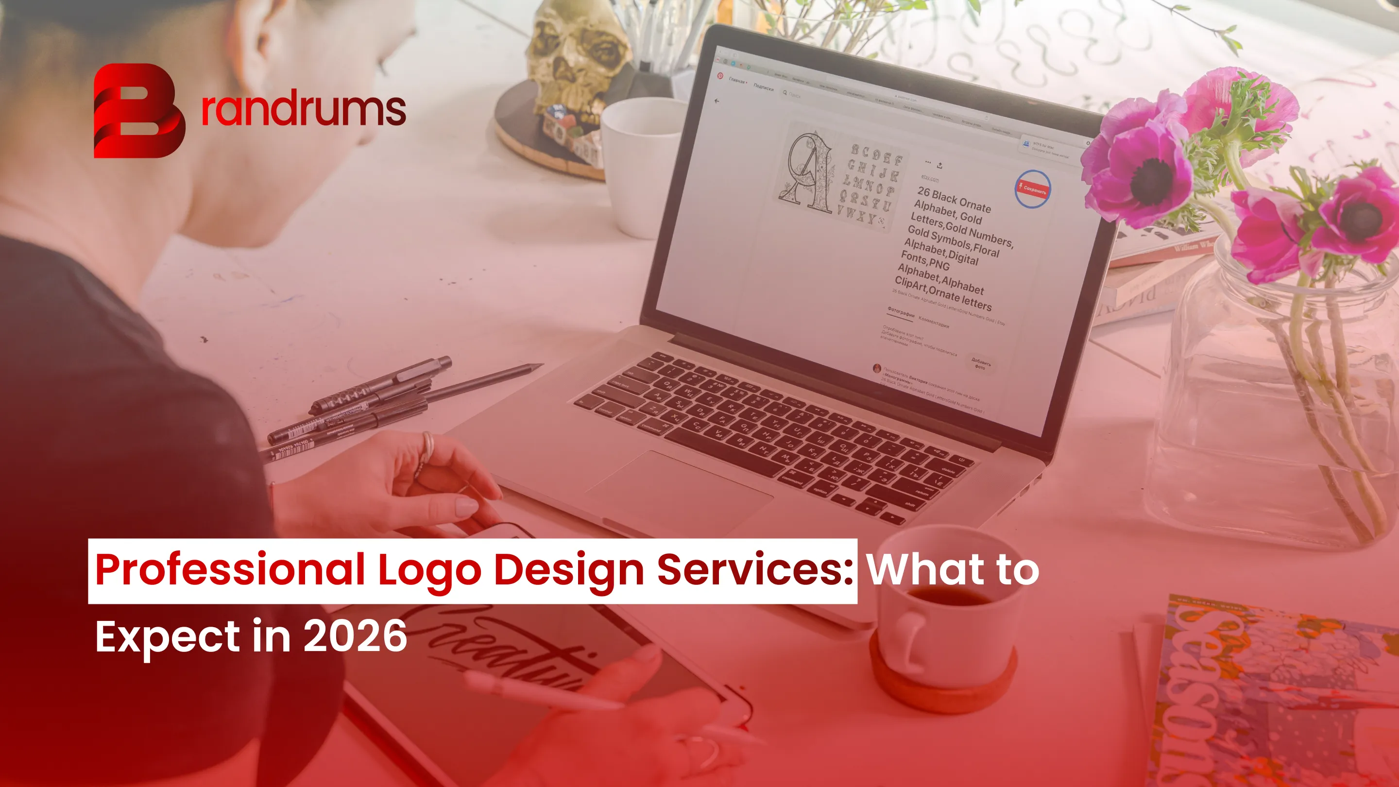 Read: Professional Logo Design Services: What to Expect in 2026 Designer reviewing logo concept sketches on a laptop next to a printed brand guidelines book